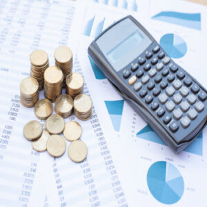 coins and a calculator on top of cash flow management worksheets